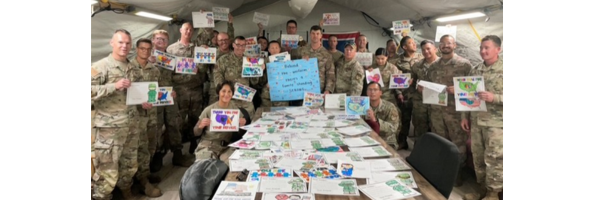 Many of the military members are holding up their own heartfelt cards with more cards laying on the table in front of them.