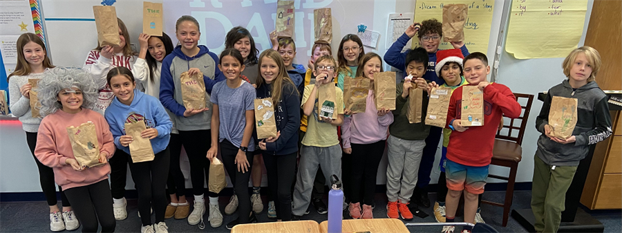 5th graders pose with bags they decorated as part of their novel project.