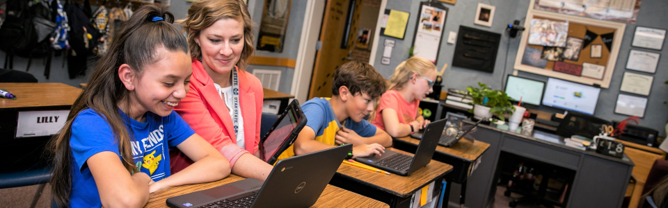 teacher helping student on a computer