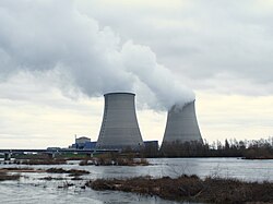 Nuclear power plant in Cattenom, France four large cooling towers expelling white water vapour against a blue sky