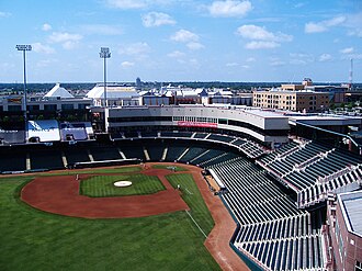 A green baseball field surrounded by a concrete concourse and green plastic seats