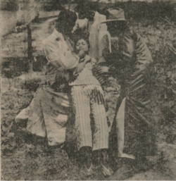 A grainy image of a man killing a woman as two men support her body