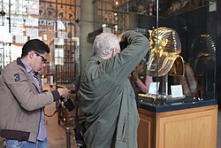 Tourist photographing Tutankhamun's golden burial mask display