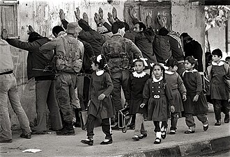 Palestinian schoolgirls returning home come across Israeli soldiers frisking a group of Palestinian men, November 1986