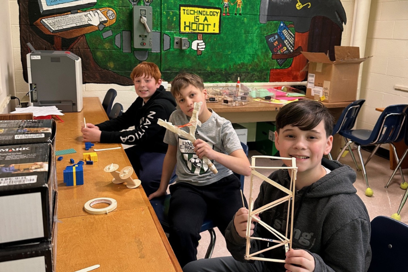 Three students show off their creations.