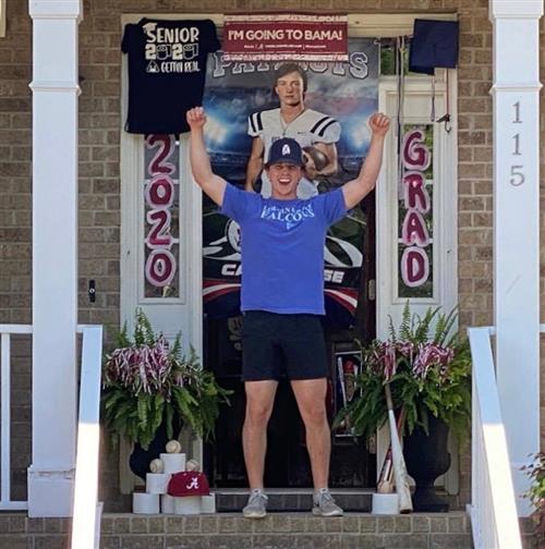 Student with arms raised in triumph in front of door with "Going to BAMA" sign 