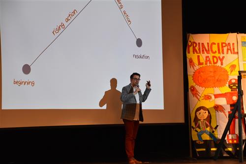 Author on stage with story diagram behind him 