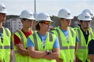 Students in hard hats listening to construction manager 