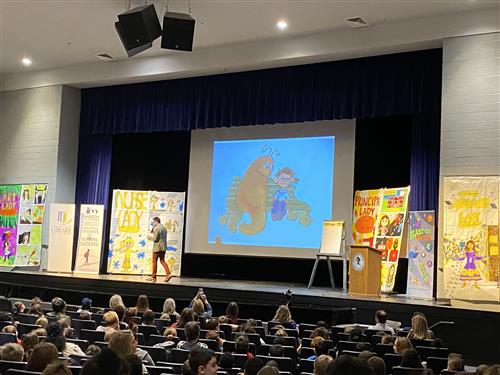 Author on stage with book props behind him 