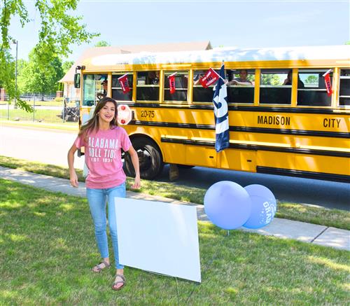 girl with Alabama Roll Tide shirt with school bus filled with teachers in background 