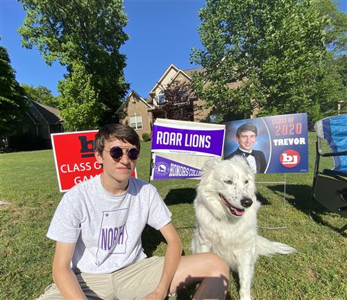 Student in front yard with dog and signs 