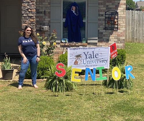 Student in front of Yale University sign in her front yard 