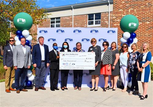 A dozen leaders, including Huntsville Mayor Tommy Battle and local school superintendents, in front of a $50,000 check