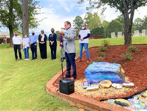 Dr. Nichols standing in rock bed accepting check on behalf of Madison City Schools 