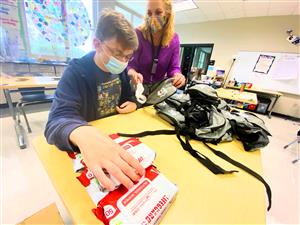 James Clemens student packing supplies under supervision of a teacher 