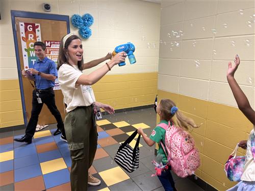 counselor creating bubbles from hand-held dispenser as students walk by