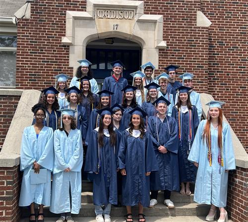 About two dozen graduates from Bob Jones and James Clemens in gowns on steps of school