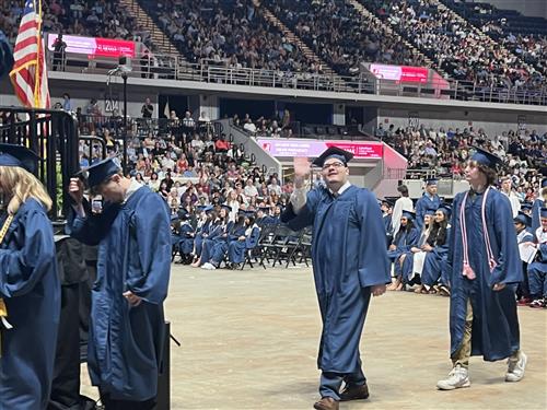 Bob Jones graduate walking toward stage waving before getting his diploma