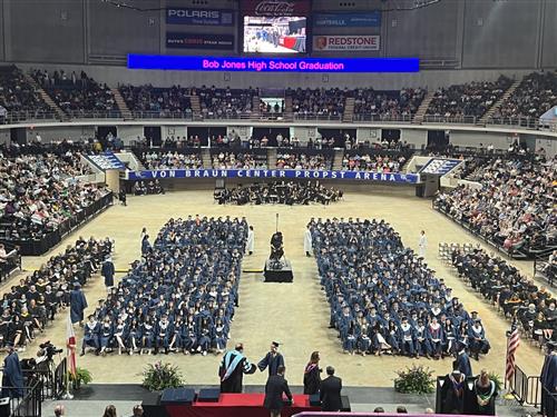wide angle view of Bob Jones graduates on the arena floor seated in rows in their caps and gowns
