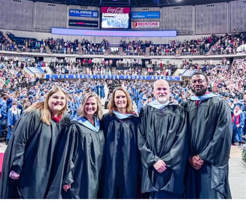 Bob Jones principal and assistant principals on stage with graduates behind them