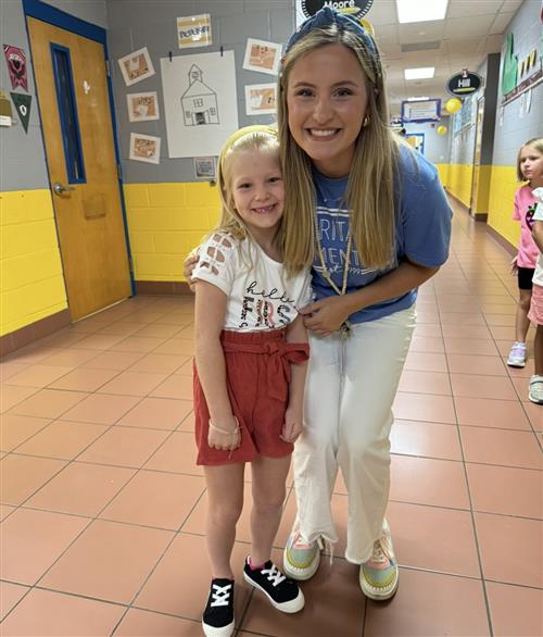 teacher posing beside student in hallway