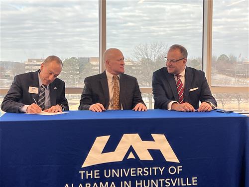 Dr. Nichols at table signing with UAH president Dr. Karr