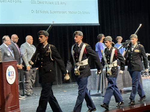 color guard exiting stage at Impact Aid ceremony at James Clemens High School