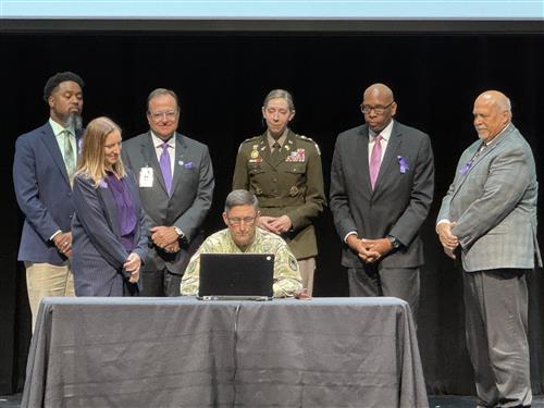 A military dad, Col. David Mullack, fills out form with superintendents behind him