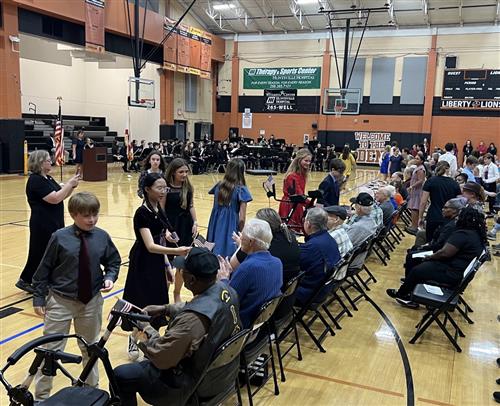 students in veterans program in gym shaking hands with veterans