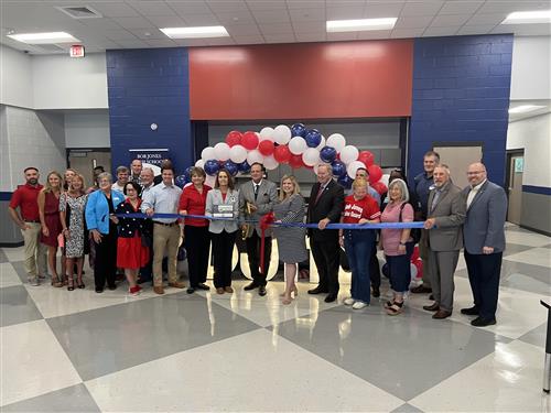 wide angle pic of about 20 dignitaries in ribbon cutting