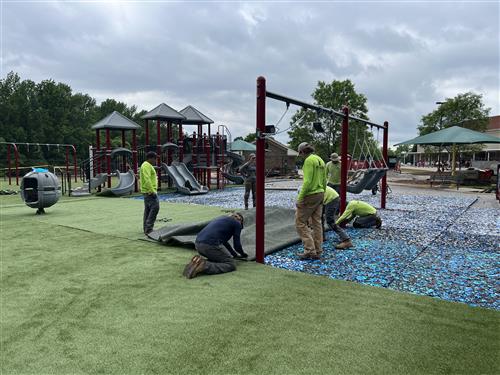 workmen laying turf on playground