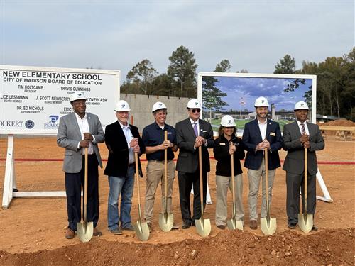 Board members and Dr. Nichols at the shovel line with the school rendering behind them