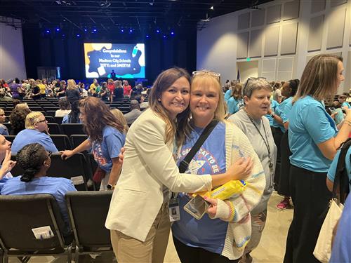 coworkers hugging in auditorium before program start