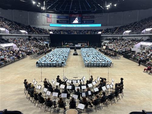 wide angle view of James Clemens graduates seated on the arena floor in caps and gowns