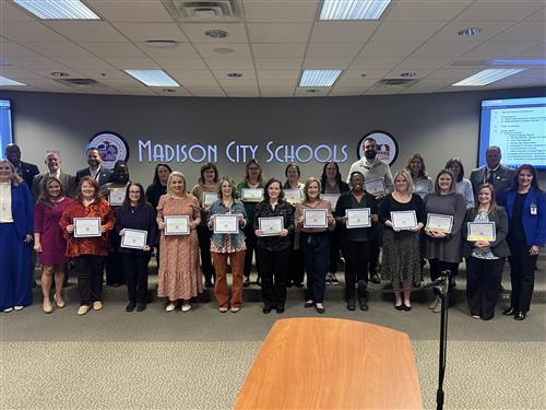 11 NBCT and 16 NBCT renewal teachers in front of board meeting