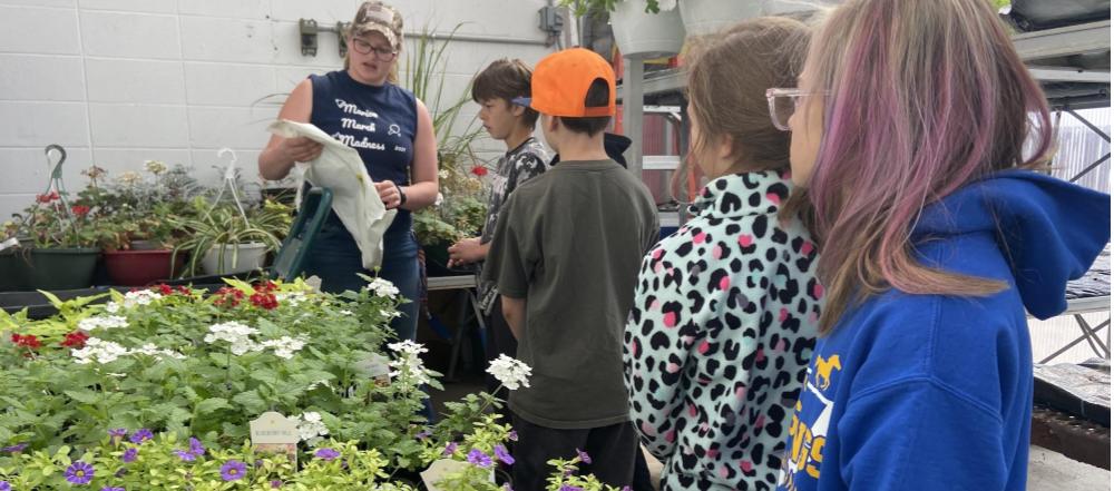 FFA member talking to younger students about the plants in the greenhouse.