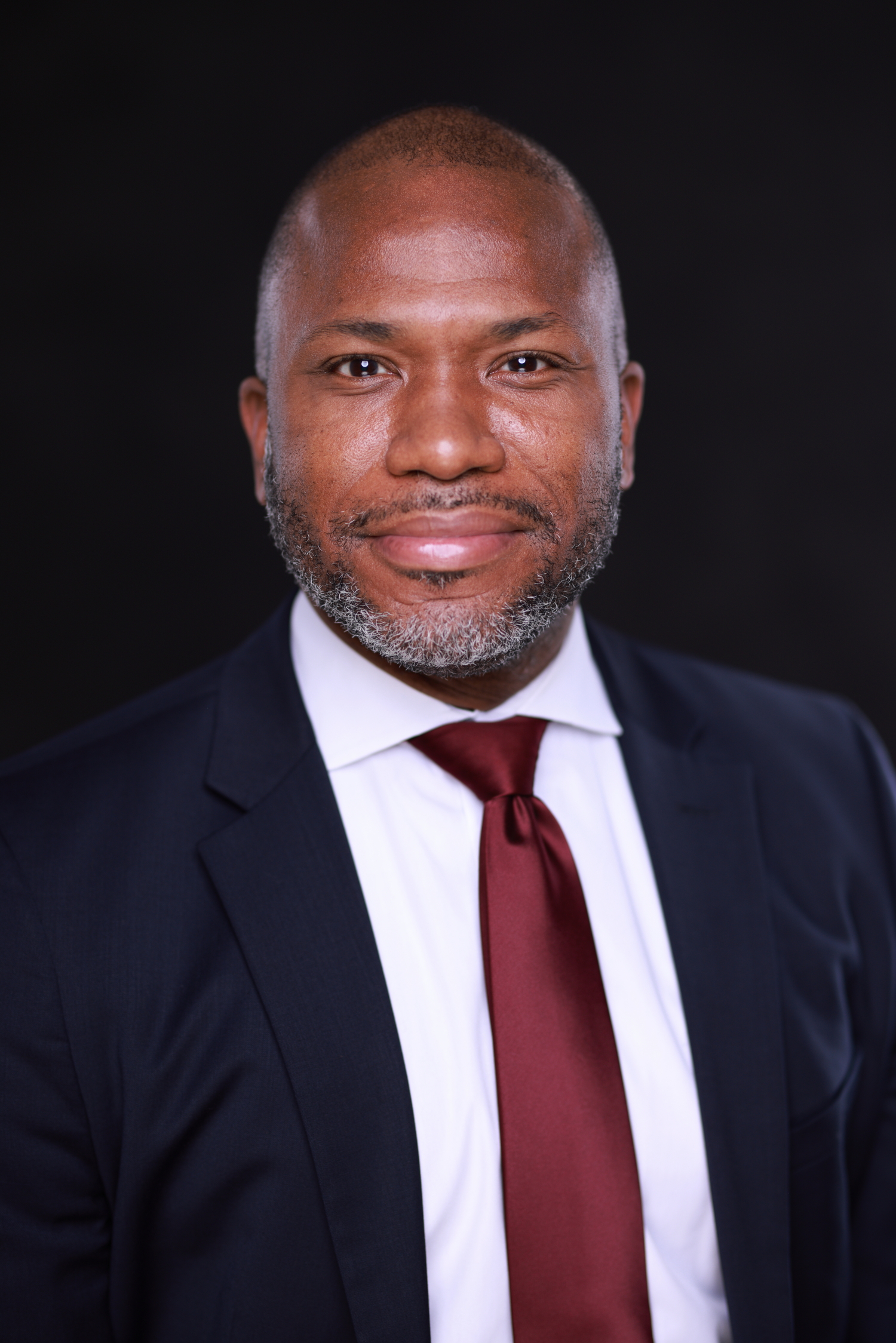 A headshot of a person in a suit and tie.