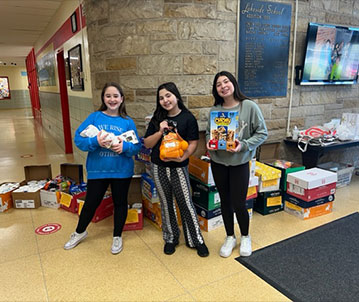 Students hold the items they raised to donate