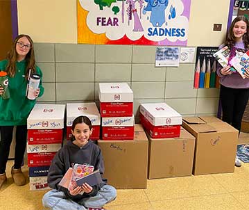 Students standing in front of boxes in hallway.