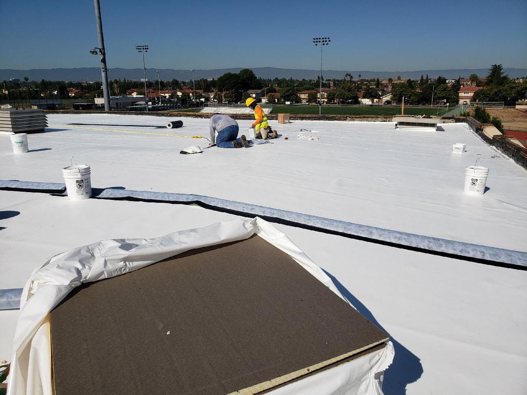 Construction workers on top of MHS roof working.