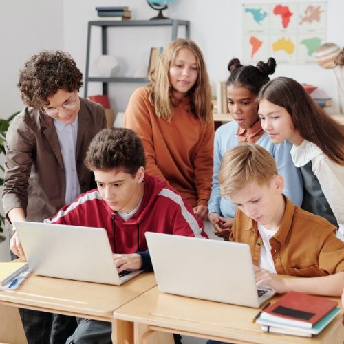 students gathered looking at laptops