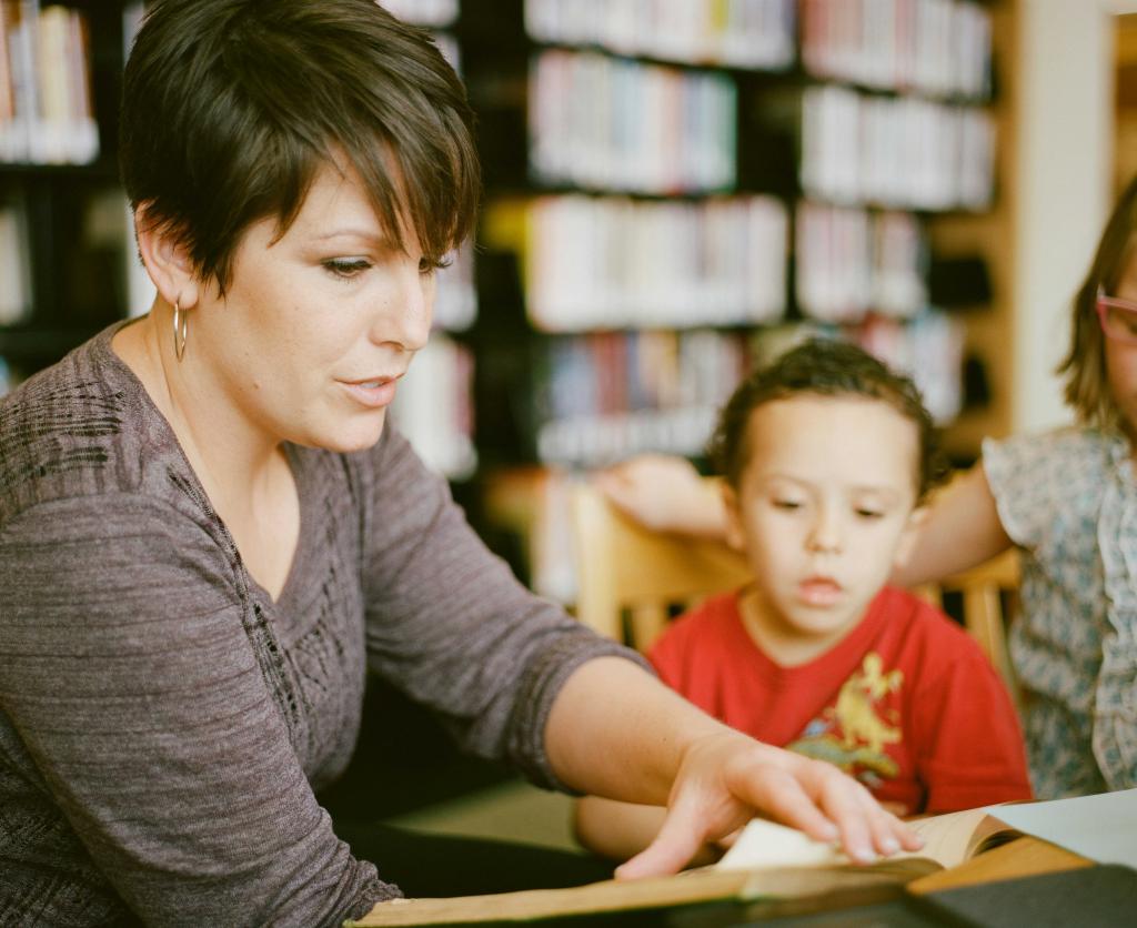 A woman is reading a book to a group of children in a library.