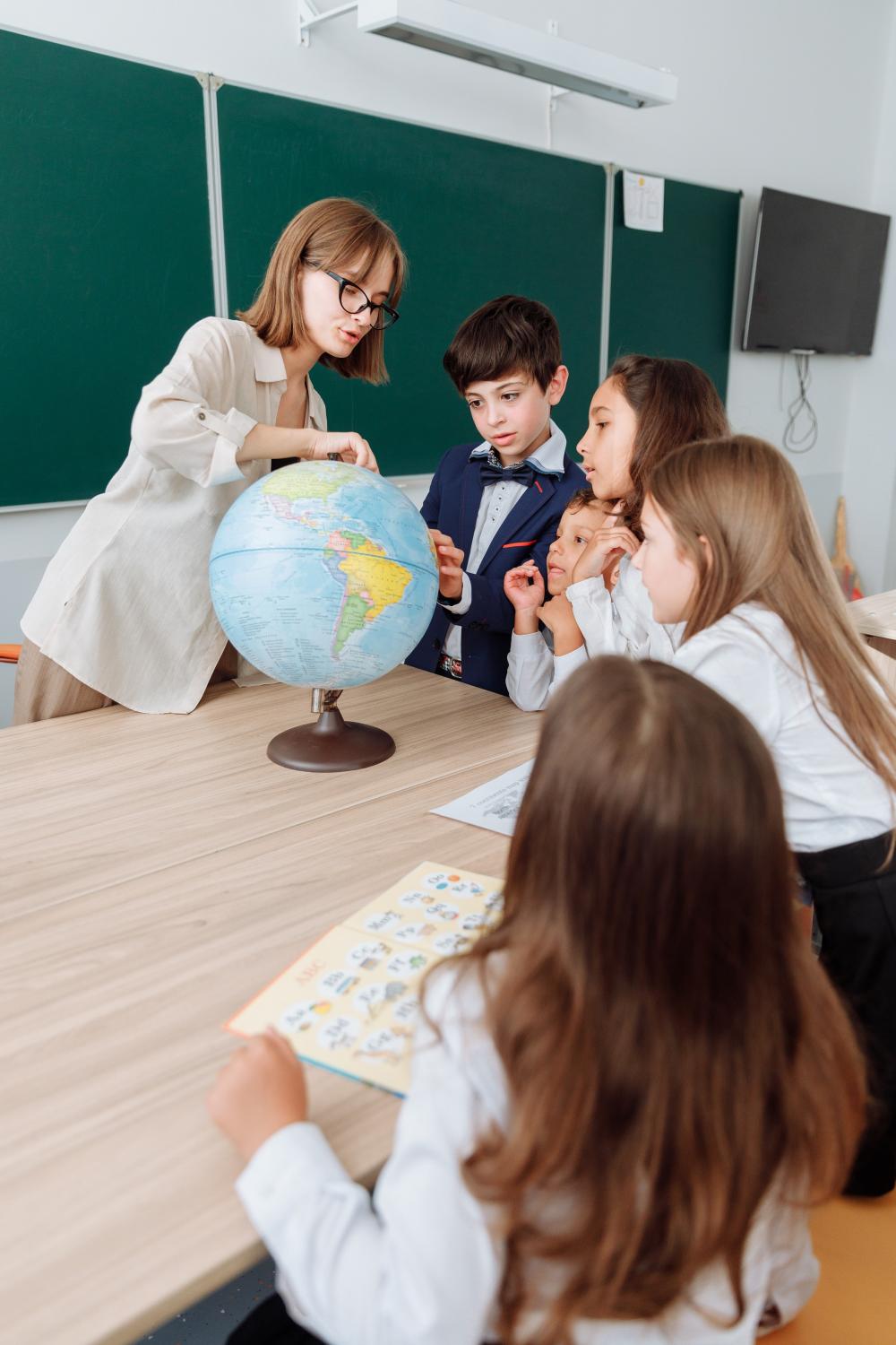 A teacher is showing a globe to her students.