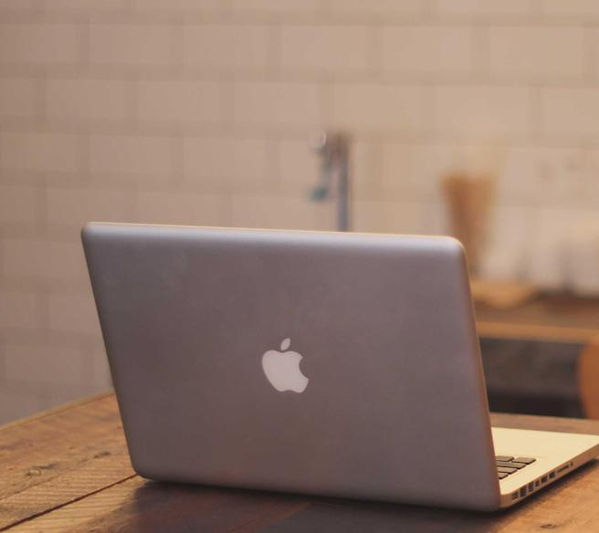 A laptop sits on a wooden table.