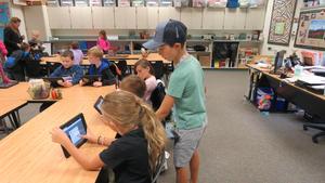 A boy helps his teammates with their iPad apps.