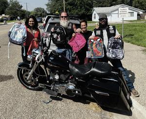 Two bikers pose with two McKinney-Vento staff in front of a motorcycle.