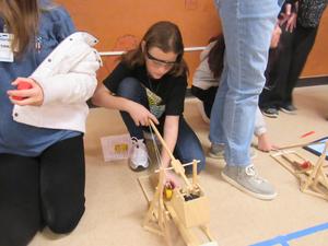 Girl loads model of a catapult.
