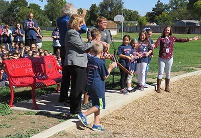 Children celebrate cutting the ribbon on their new bench.