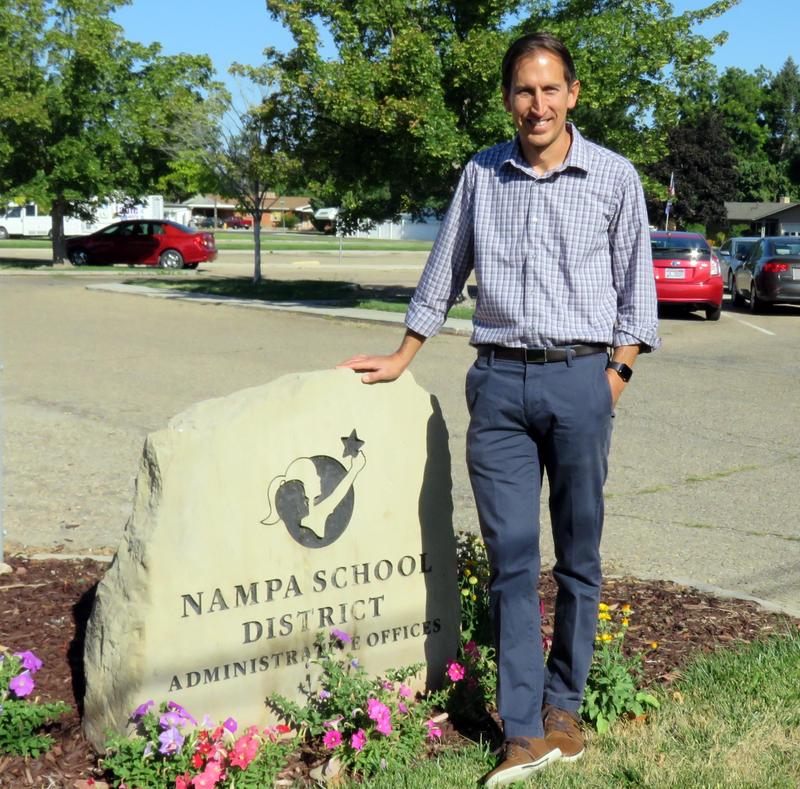 Justin Pickens stands next to the etched rock with the district name and logo.