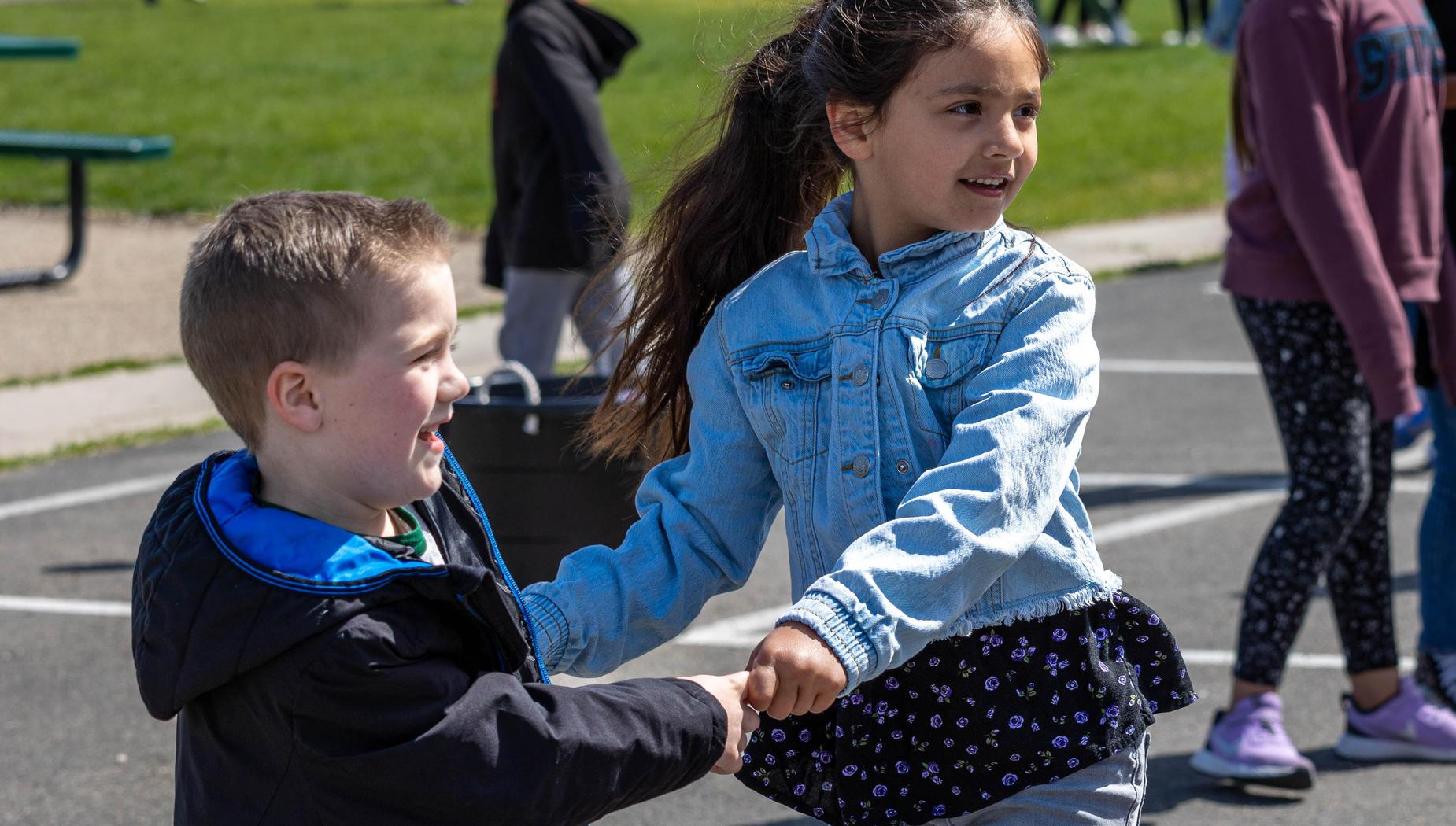 Boy and girl hold hands while standing on school track.